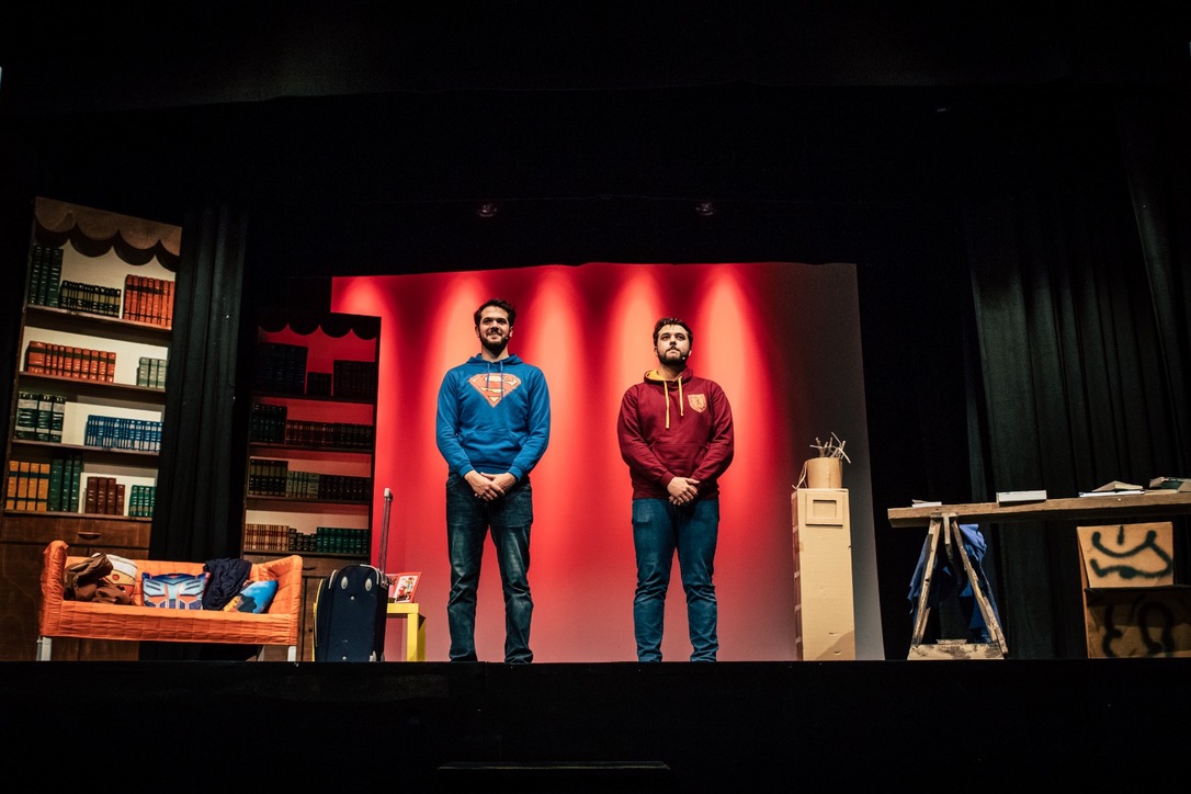 Fabrizio e Federico sul palco di Fratelli ma non troppo, davanti alla scenografia rossa con divano e librerie