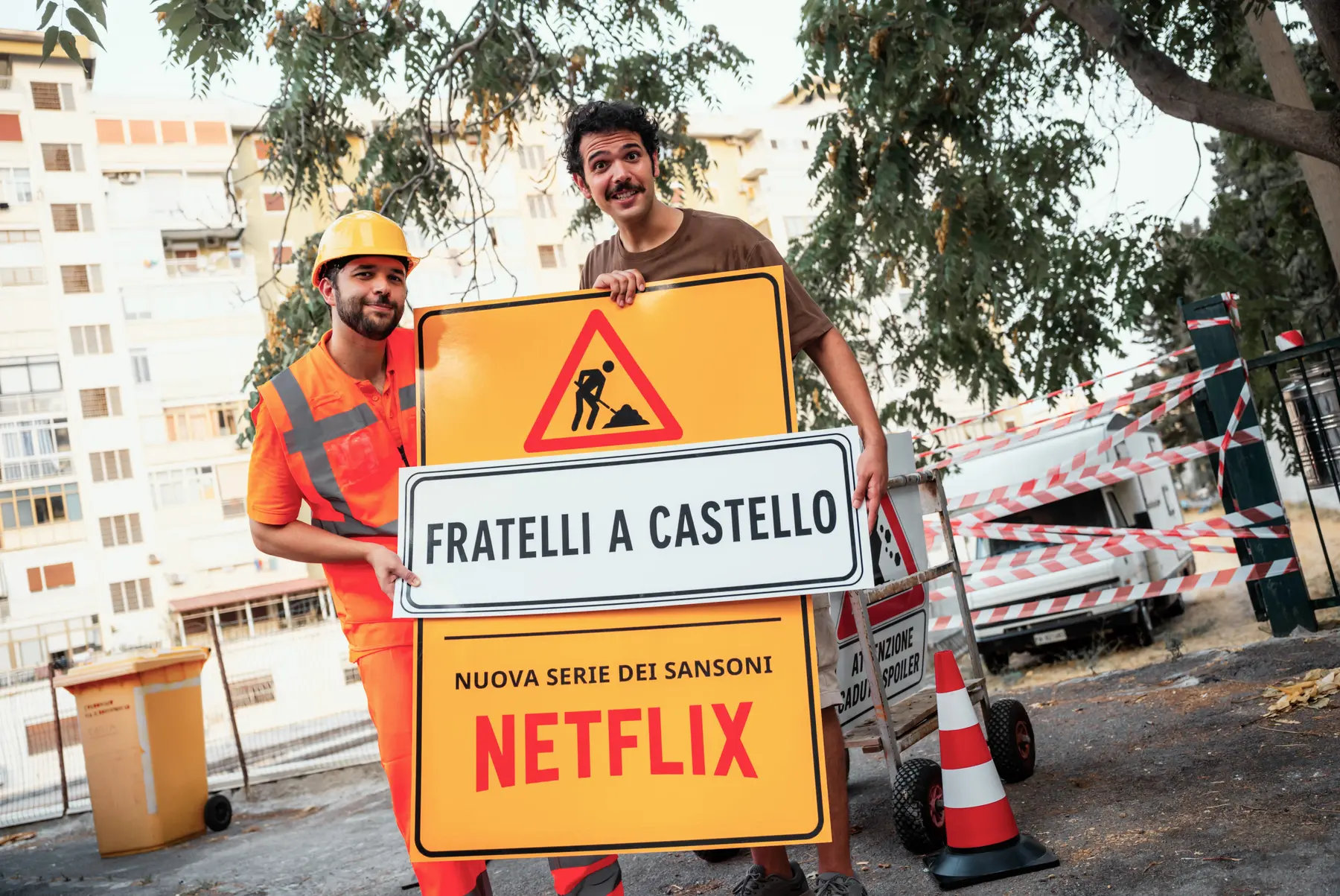 I Sansoni in abiti da cantiere tengono un cartello di Fratelli a Castello, nuova serie Netflix