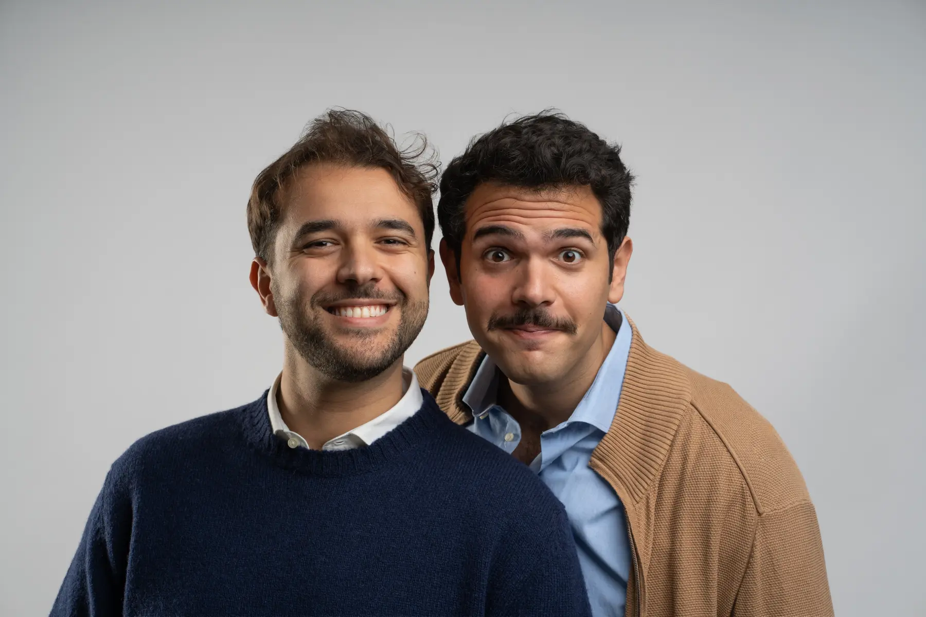 Fabrizio e Federico Sansone sorridono insieme davanti a uno sfondo chiaro